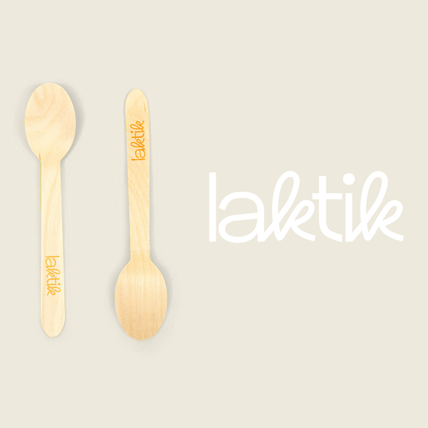 Dues culleres de fusta amb un logo gravat i el mateix logo en blanc al costat, sobre un fons beige.
